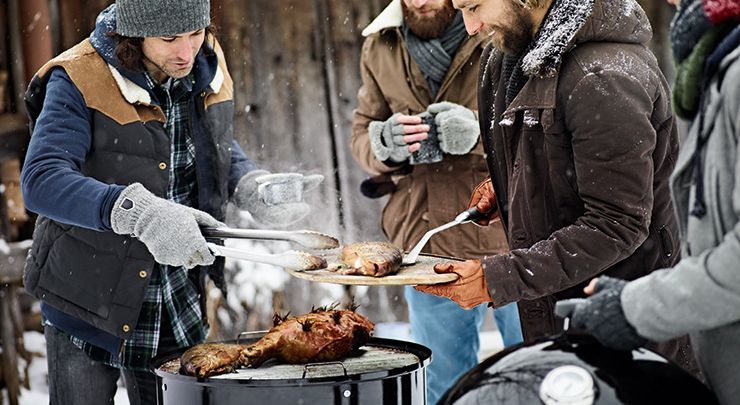 Menschen grillen im Winter mit einem Holzkohlegriller.