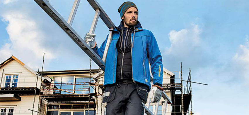 Mann arbeitet mit einem Hammer in einer Arbeitskleidung und trägt eine Leiter